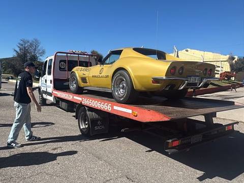 Auto deportivo clásico amarillo cargado en una grúa