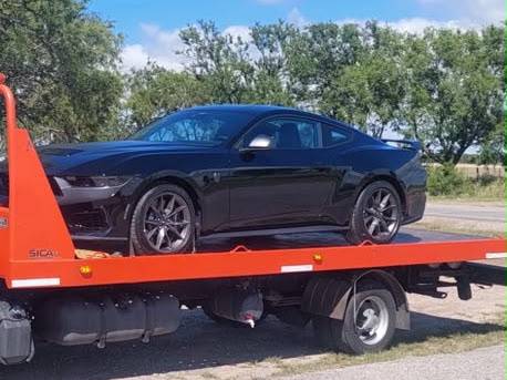 Auto deportivo negro sobre la plataforma de una grúa
