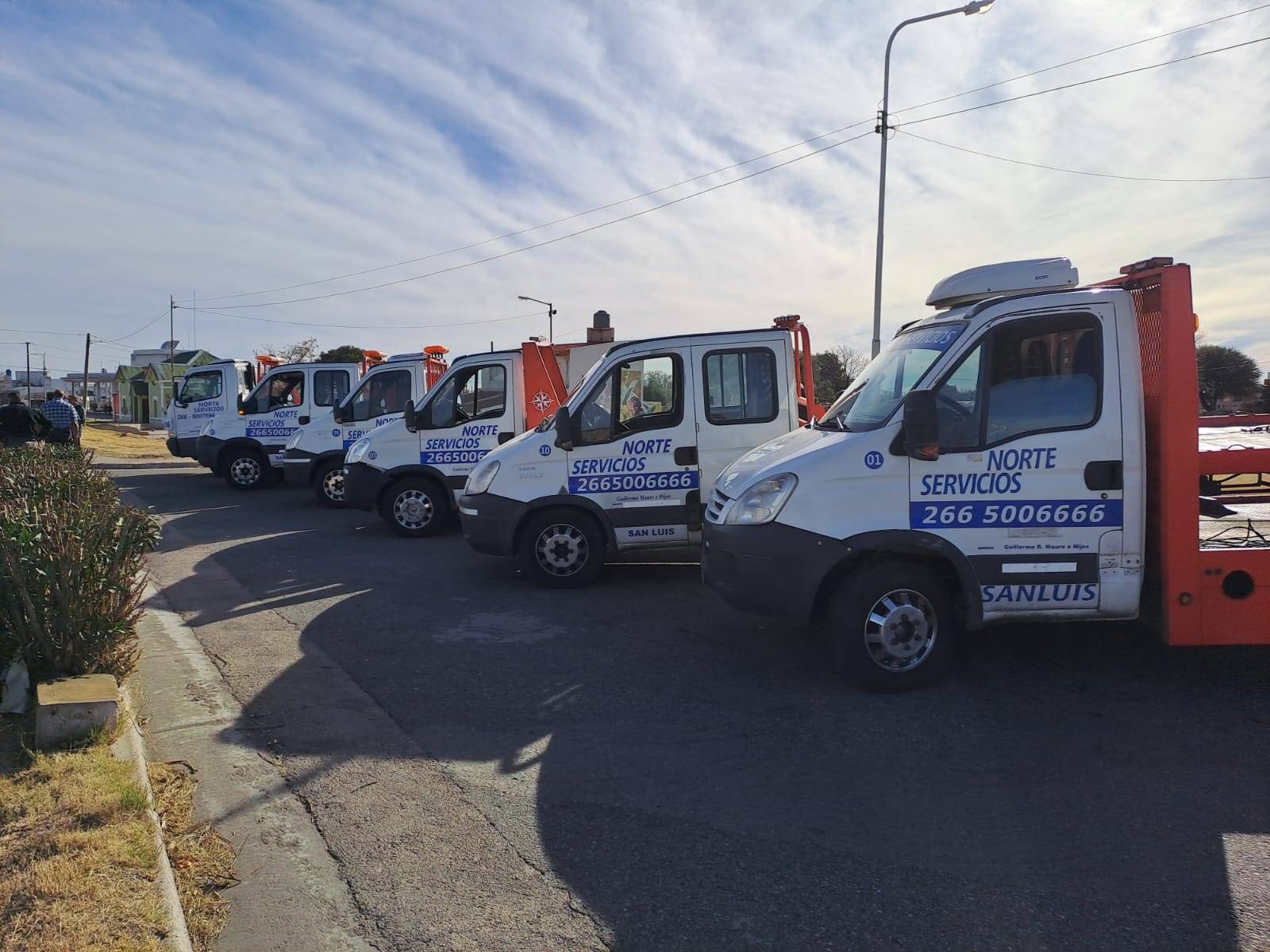 Grúas de plataforma de la flota alineadas, con los números de teléfono pintados en las puertas