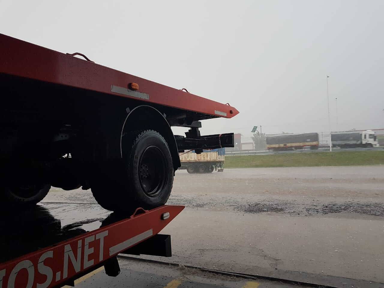 Plataforma naranja de una grúa de la flota trabajando bajo la lluvia en la ruta