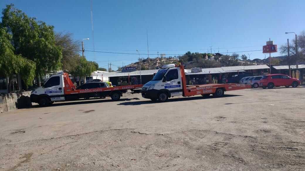 Dos grúas de plataforma de la flota remolcando vehículos a la vera del camino